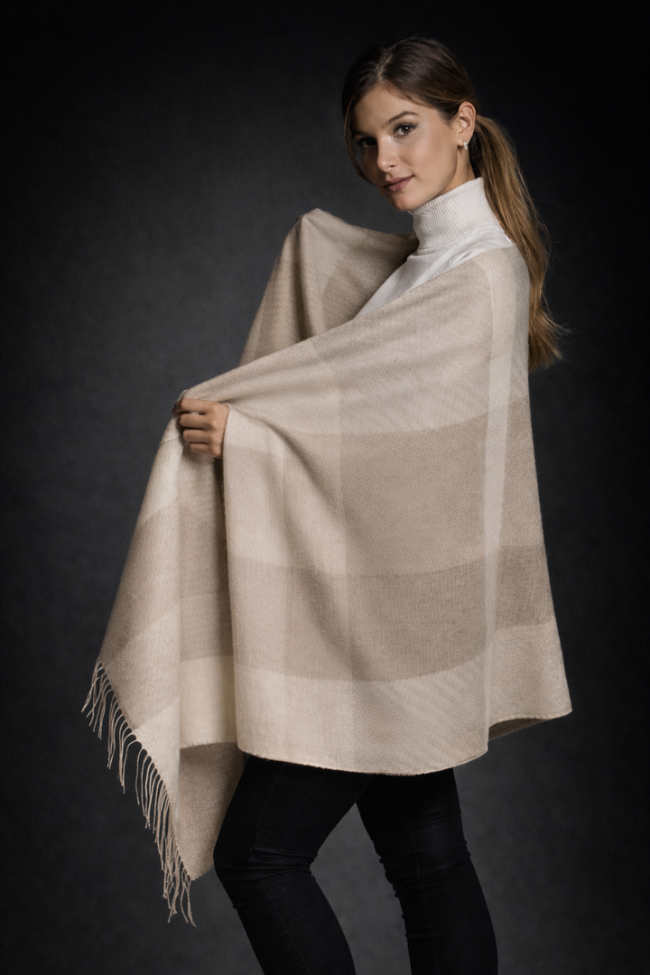 Woman wearing a beige checkered shawl against a dark background