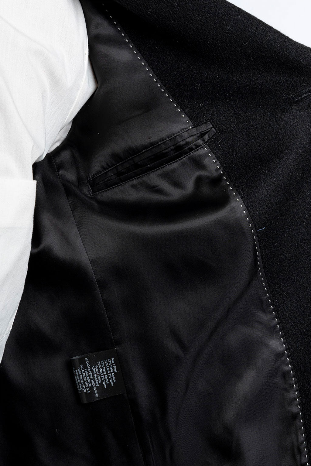 Close-up of a black jacket with a visible brand label on a white background