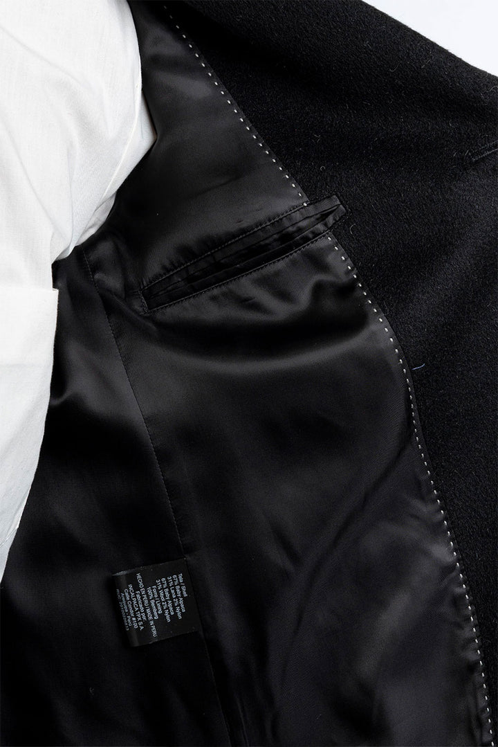 Close-up of a black jacket with a visible brand label on a white background